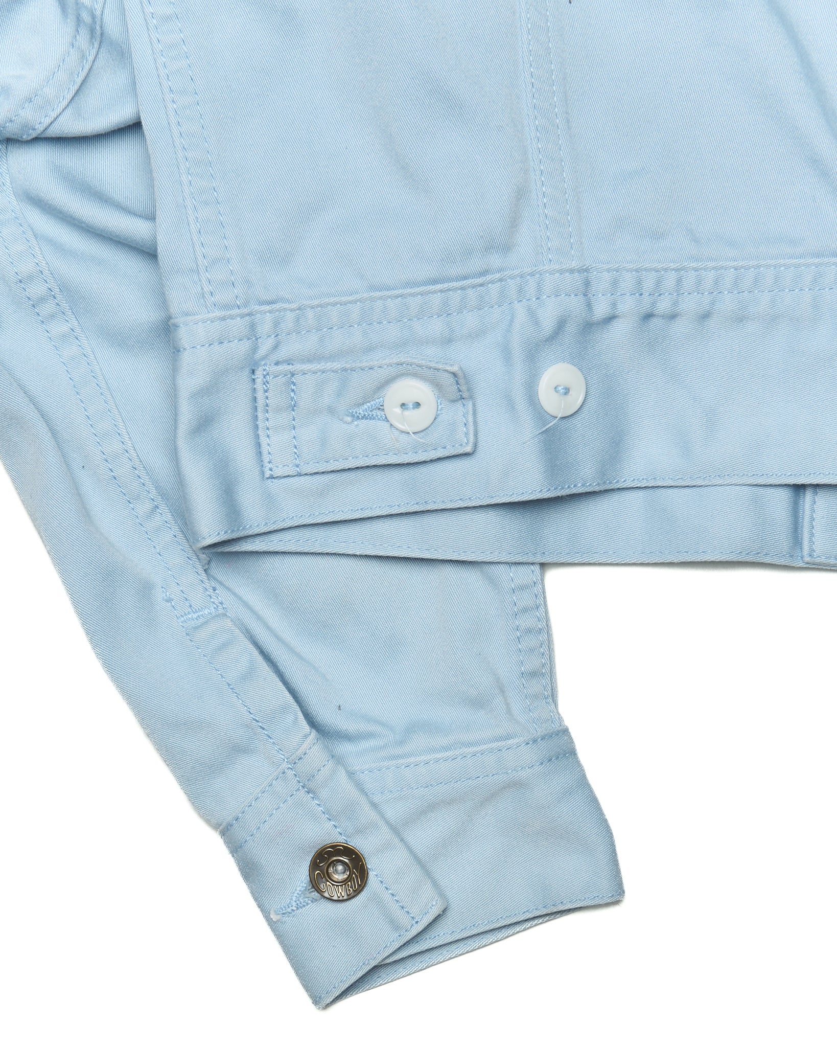 Light blue denim jacket with button details on a white background