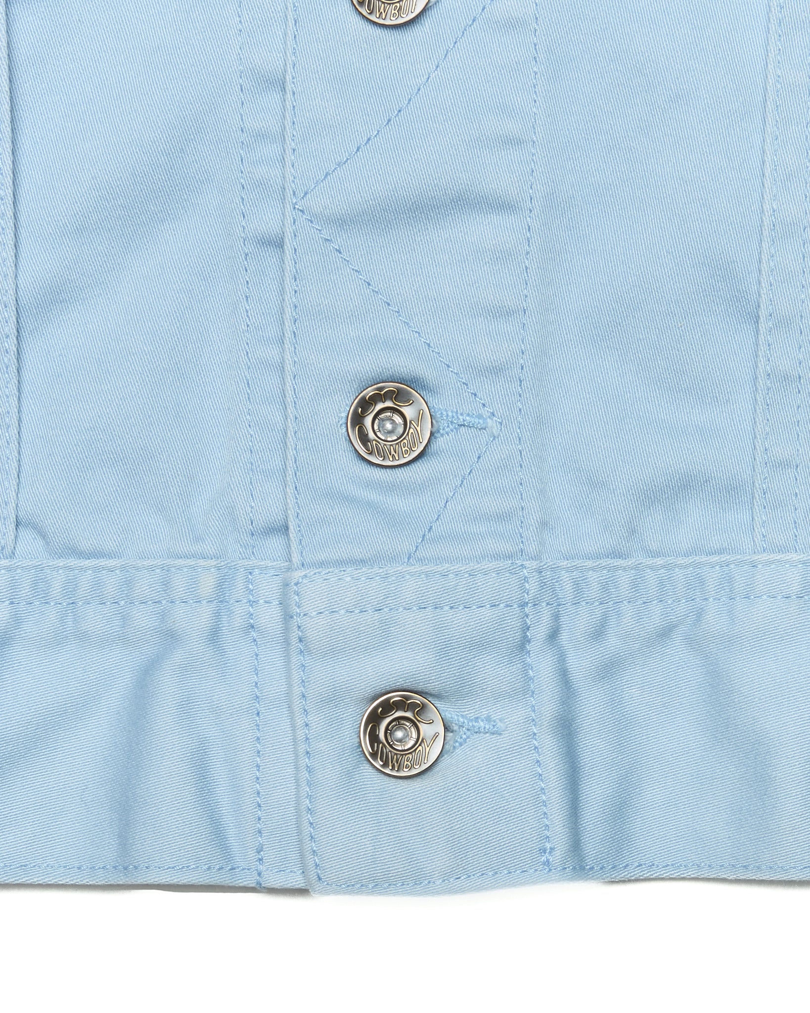 Close-up of a light blue fabric with metal buttons on a white background