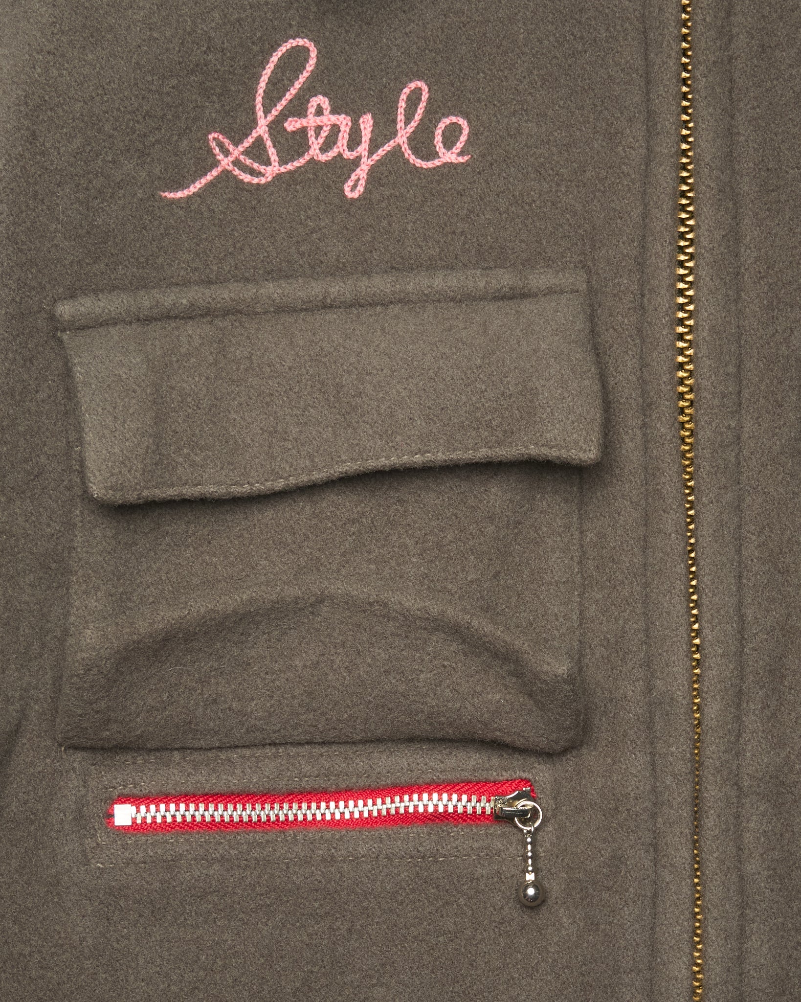 Gray jacket with a pink 'Style' embroidery and a red zipper.
