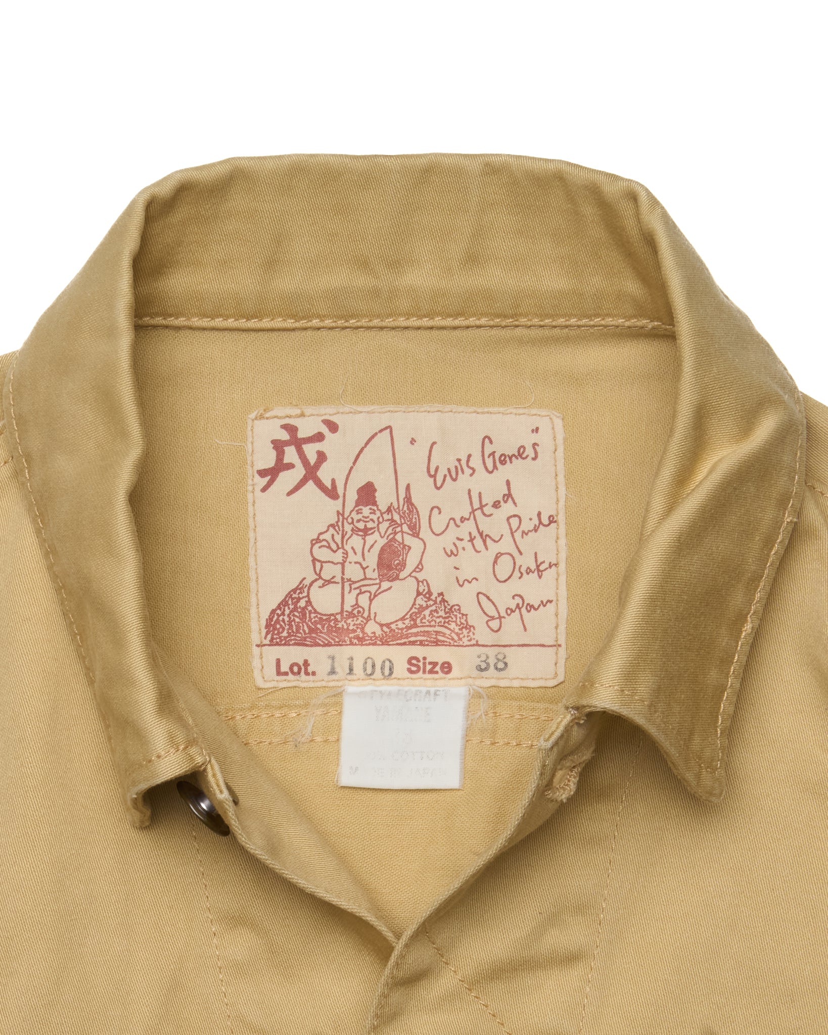 Close-up of a beige shirt collar with a brand label featuring text and graphics.