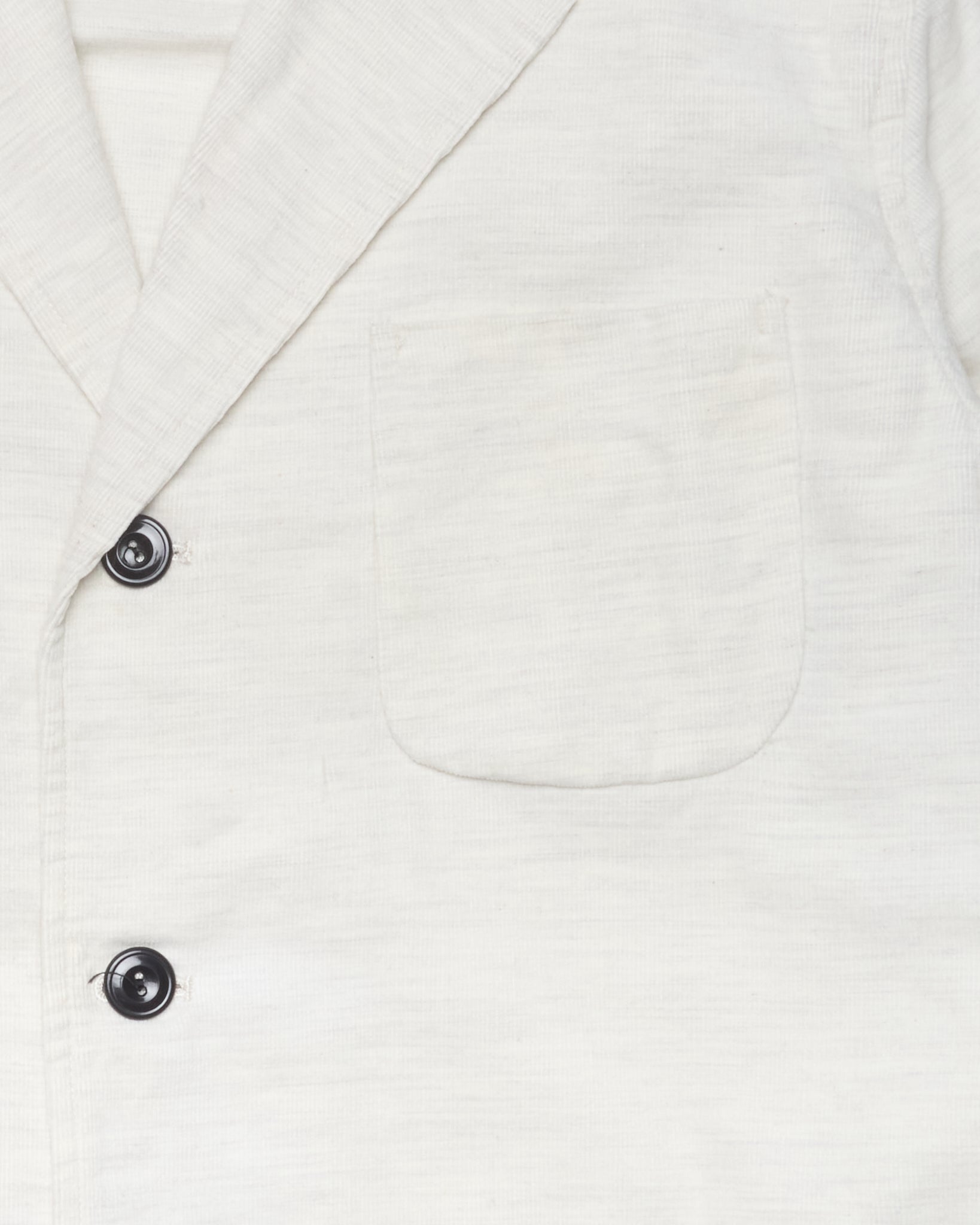 Close-up of a white blazer with a button on a white background