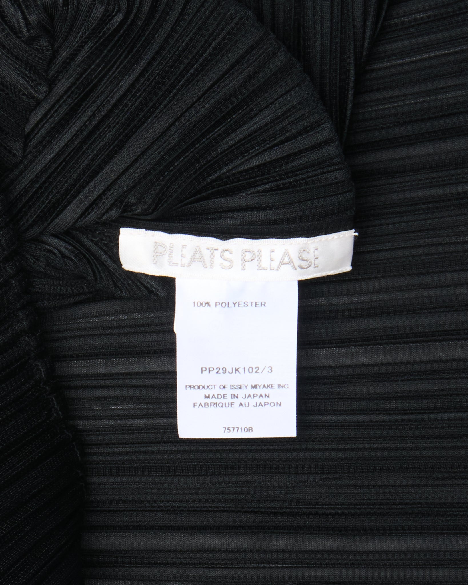 Black pleated garment with a label on a black background