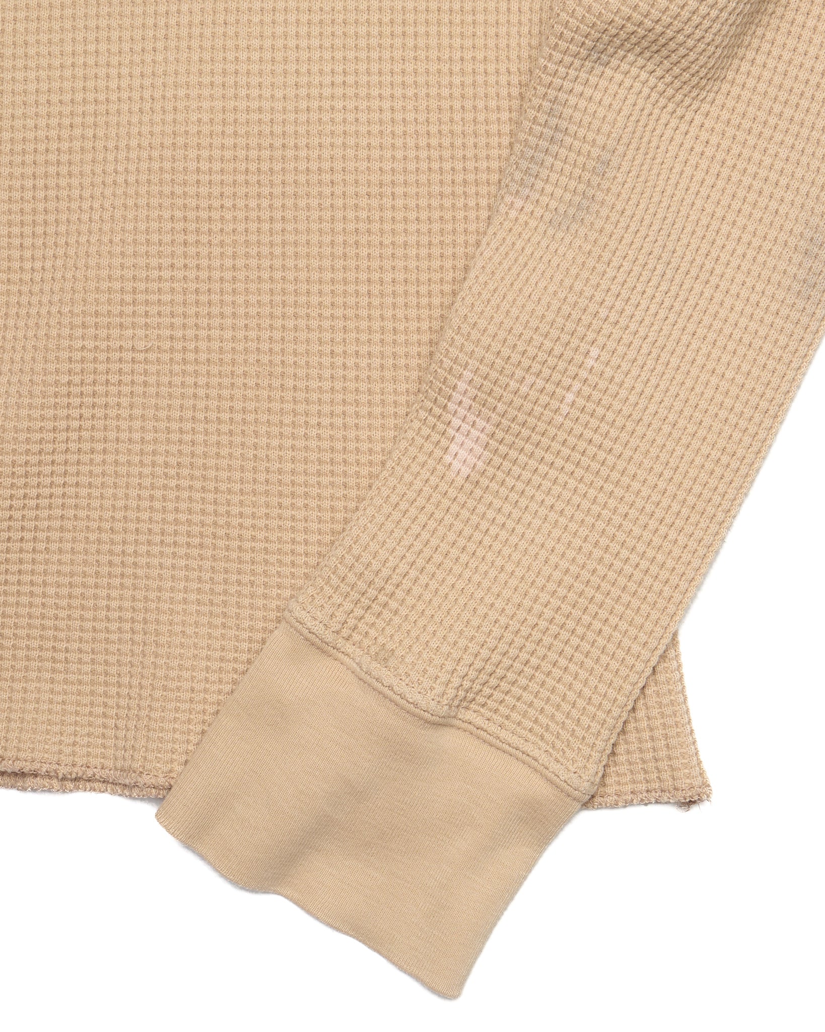 Close-up of a beige textured fabric garment on a white background