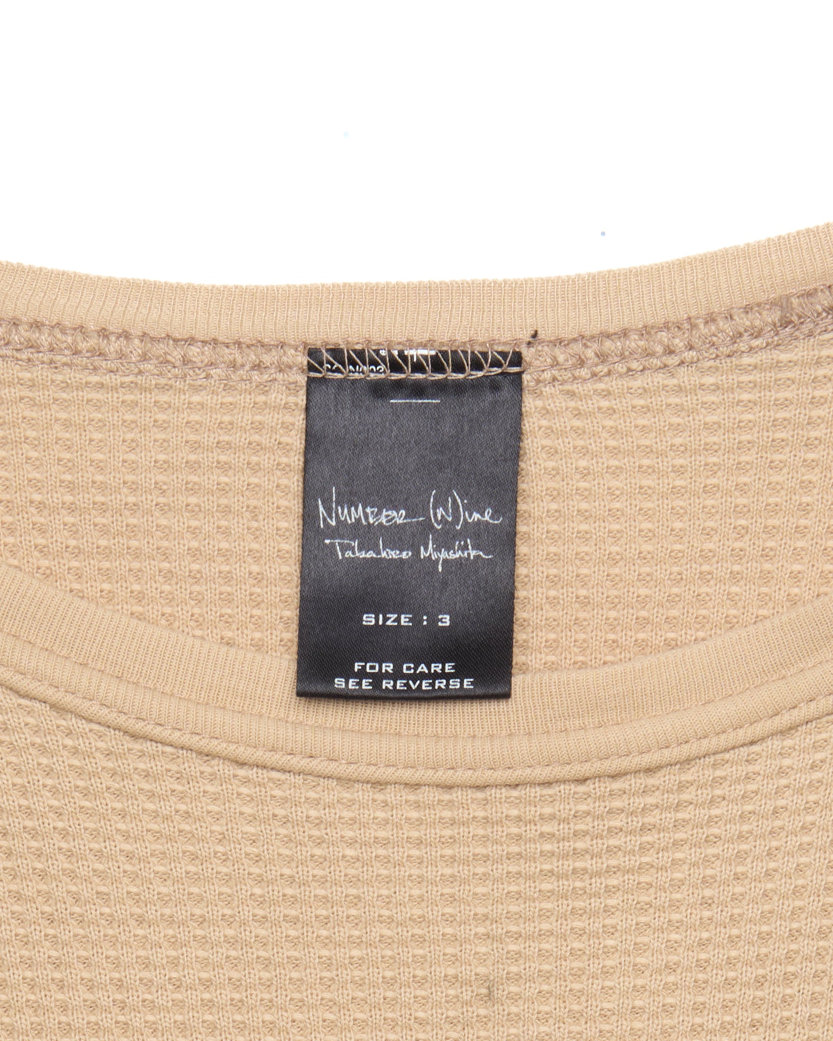 Close-up of a beige garment with a label on a white background