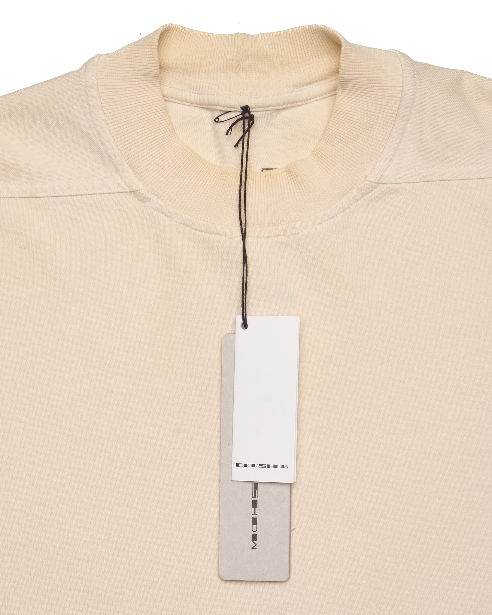 Beige sweater with a white tag on a light beige background