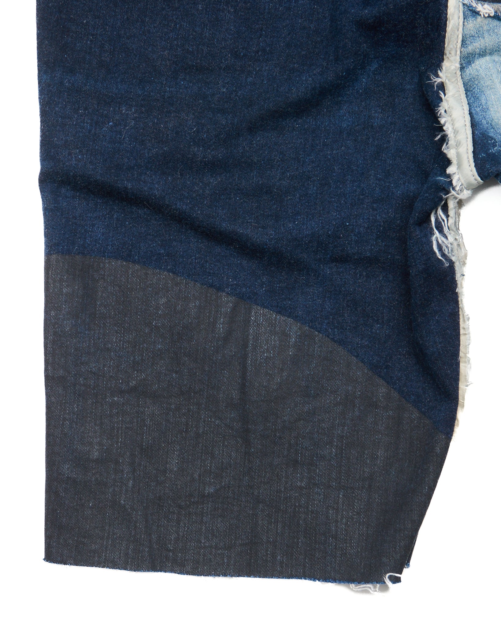 Close-up of a blue denim fabric with a frayed edge on a white background