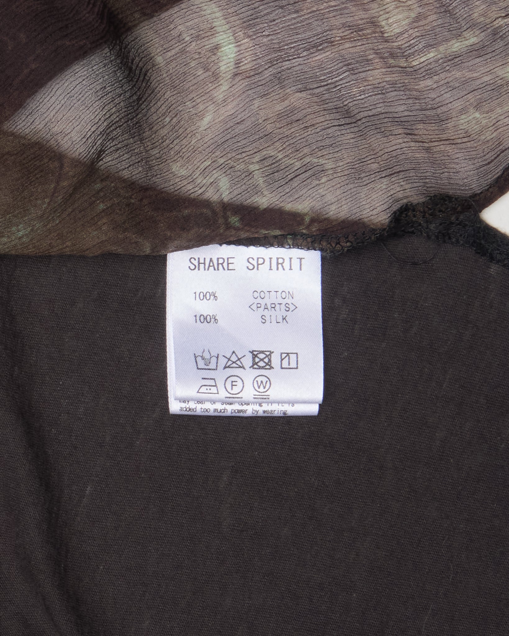 Clothing label on a dark fabric background with 'Share Spirit' branding.
